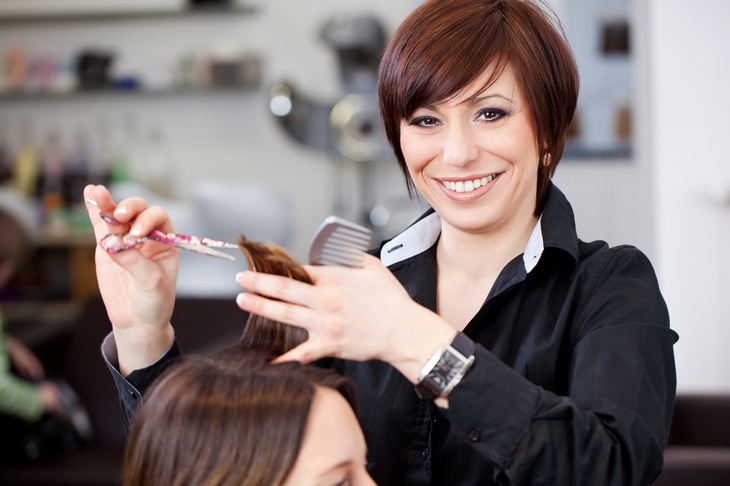 Lächelnde Friseur:in beim Haareschneiden